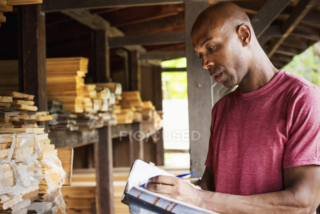 Hombre sosteniendo la carpeta y escribiendo notas - foto de stock