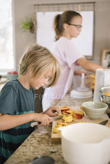 Хлопчик нарізкою фруктів — стокове фото