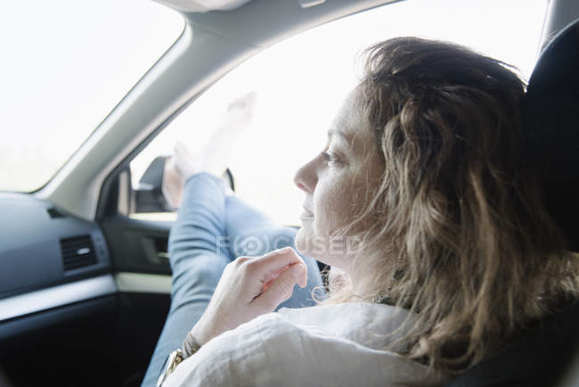 Mujer en un coche en un viaje por carretera - foto de stock
