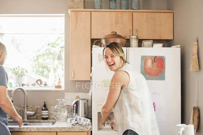 Blond woman standing at fridge — Stock Photo