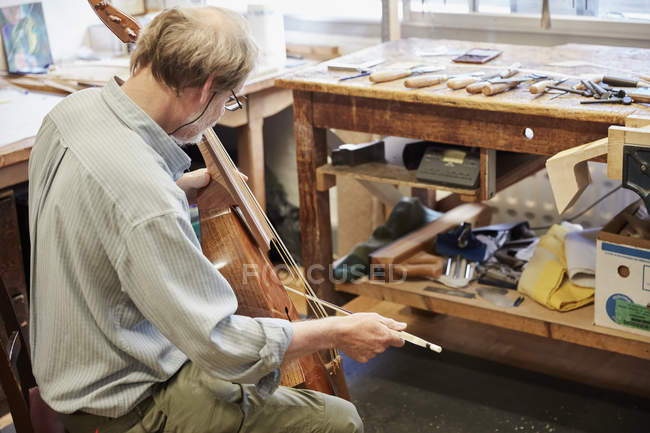 Fabricante de violino em oficina tocando um instrumento — Fotografia de Stock