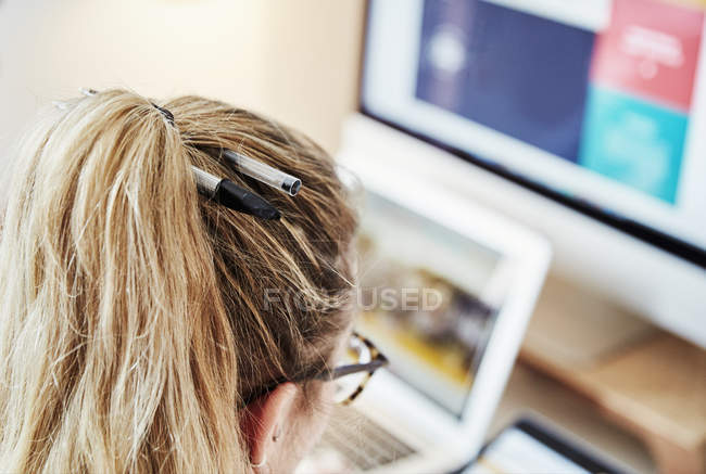 Frau am Arbeitsplatz mit zwei Kugelschreibern im Haar. — Stockfoto