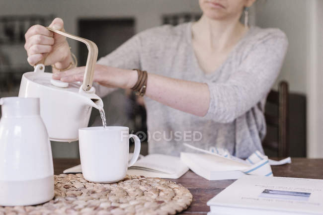 Woman pouring hot water into mug — Stock Photo