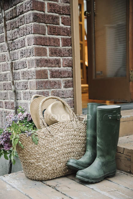 Basket and straw hat by a doorway. — Stock Photo