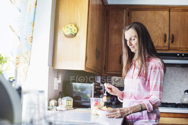 Senior woman standing in a kitchen — Stock Photo