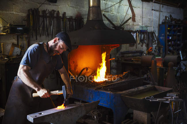 Forgeron frappe une longueur de métal chaud — Photo de stock
