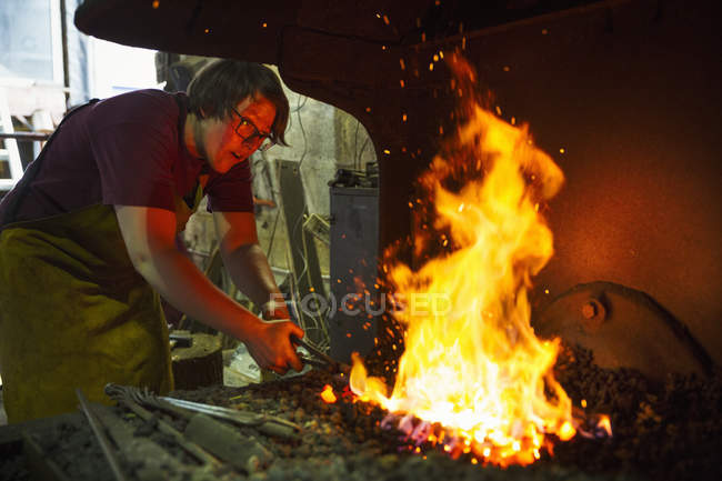 Fabbro riscalda qualcosa in una fornace . — Foto stock