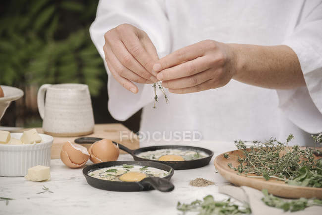 Женщина добавляет травы в яйца — стоковое фото