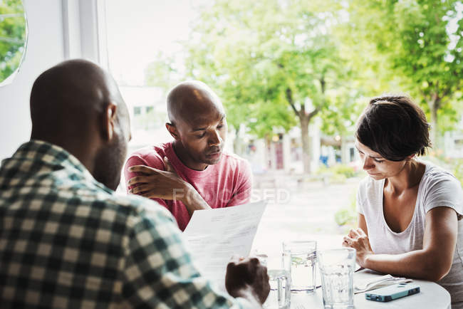 Hombres y mujeres almorzando en la cafetería - foto de stock