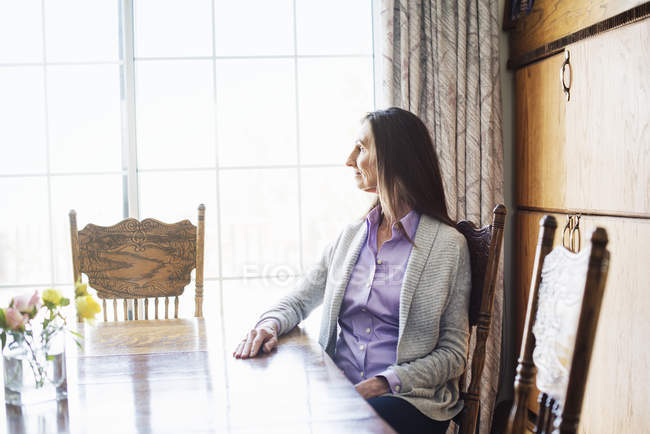 Старшая женщина сидит за обеденным столом . — стоковое фото