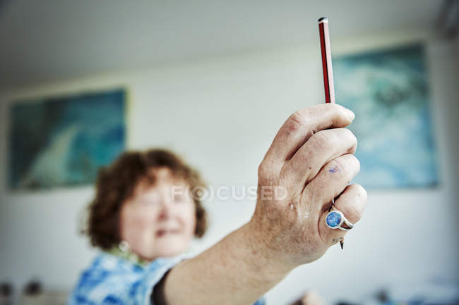 Woman artist holding up pencil in hand — Stock Photo