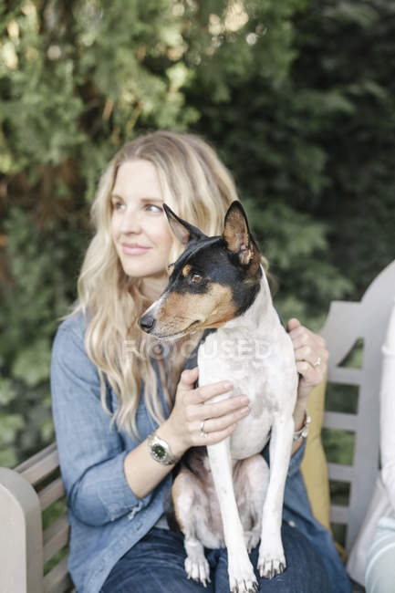 Жінка сидить на лавці з собакою — стокове фото