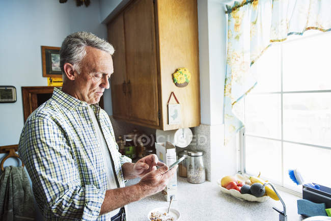 Senior man standing in a kitchen — Stock Photo