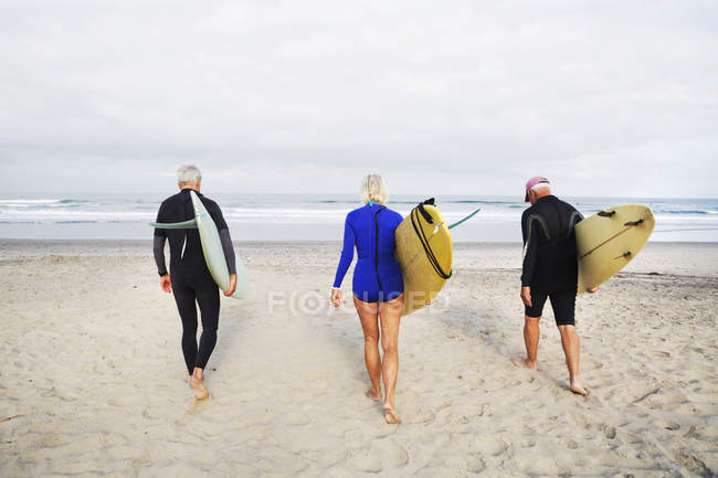 Donne e uomini anziani che trasportano tavole da surf
. — Foto stock