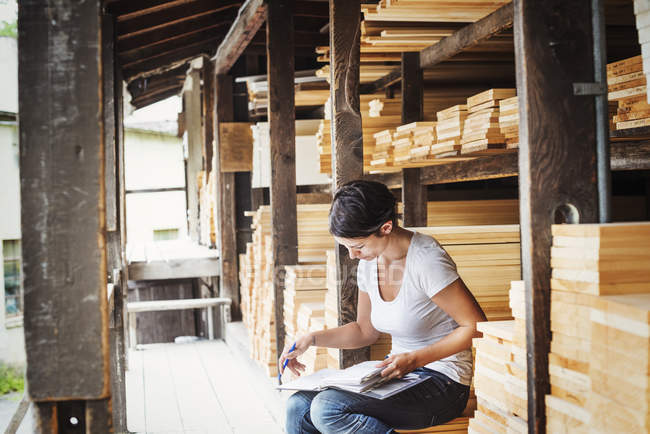 Mujer sosteniendo carpeta y haciendo notas - foto de stock