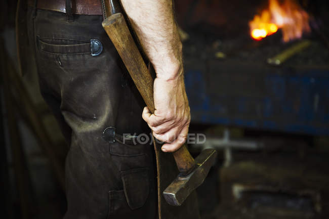 Man holding a hammer in a workshop. — Stock Photo