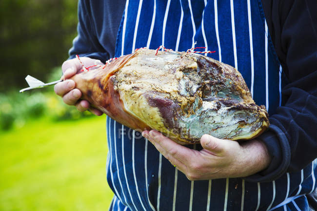 Butcher holding large cured ham — Stock Photo