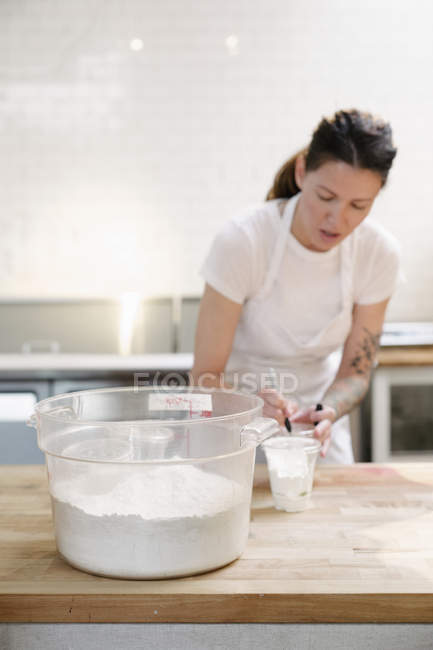 Женщина в пекарне, измеряющая муку . — стоковое фото
