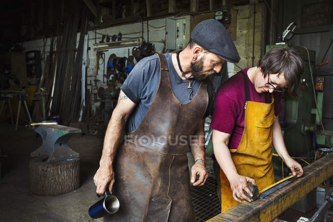 Blacksmiths measure a length of metal — Stock Photo