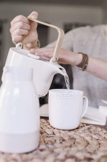 Donna versando acqua calda in tazza — Foto stock