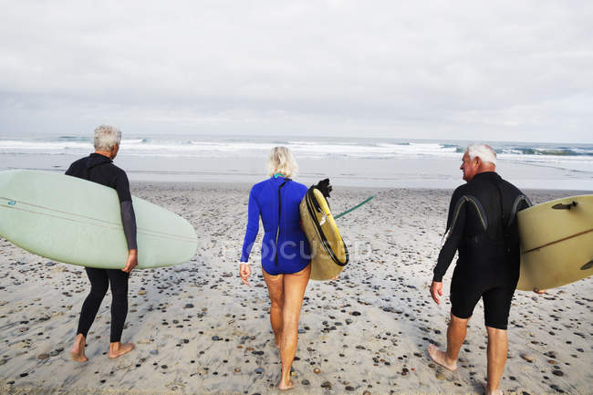 Senior femme et les hommes portant des planches de surf . — Photo de stock