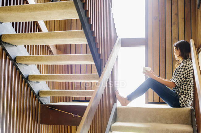 Femme assise sur un escalier en bois — Photo de stock