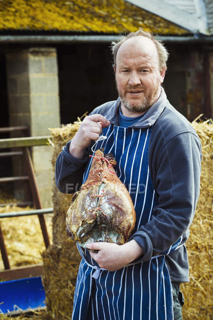 Butcher holding large cured ham — Stock Photo