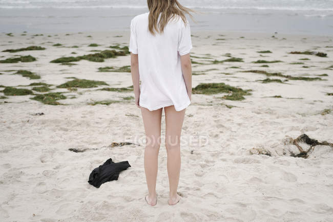 Дівчина стоїть на піщаному пляжі — стокове фото