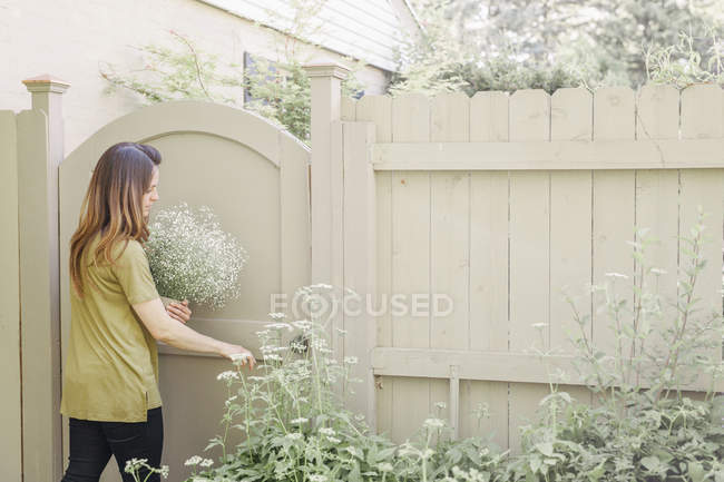 Mulher entrando em um jardim através de um portão — Fotografia de Stock