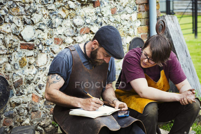 Hombre y mujer escribiendo en un cuaderno - foto de stock