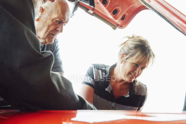 Mulher e homem sênior reparando um carro — Fotografia de Stock
