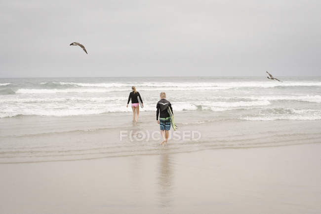 Boy and girl carrying bodyboards — Stock Photo