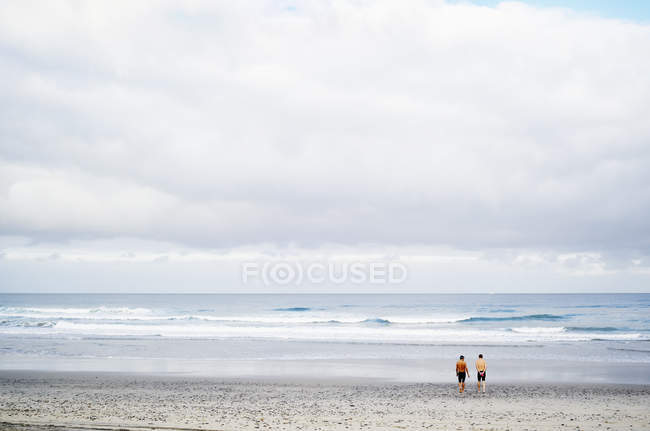 Мужчины, стоящие на песчаном пляже — стоковое фото