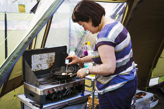 Mujer parada en la estufa de camping - foto de stock