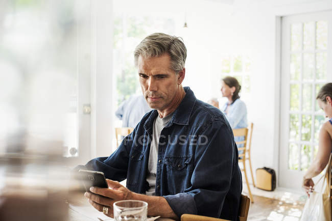 Hombre sentado en una cafetería - foto de stock