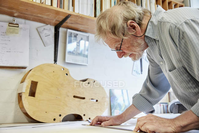 Violin maker at drawing board drawing — Stock Photo