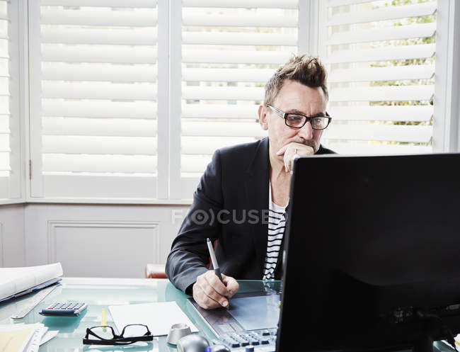 Geschäftsmann blickt auf Computerbildschirm — Stockfoto