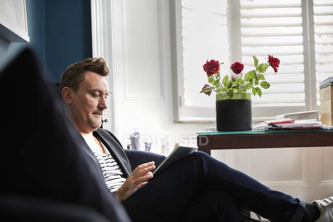 Hombre de negocios sentado en una oficina usando tableta digital - foto de stock