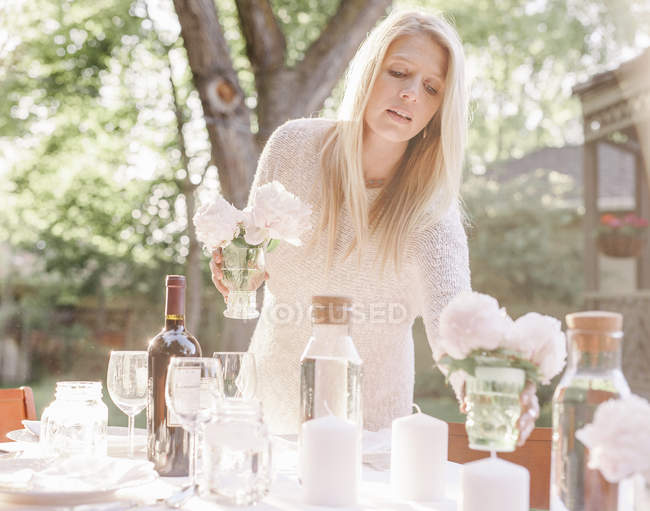 Donna apparecchiare una tavola in un giardino — Foto stock