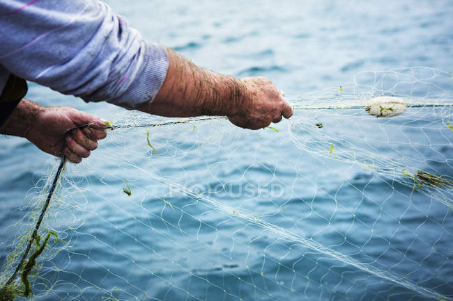 Fisherman pulling the net out of the water. — Stock Photo