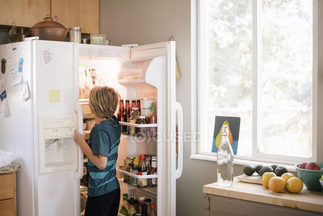 Boy standing at open fridge — Stock Photo