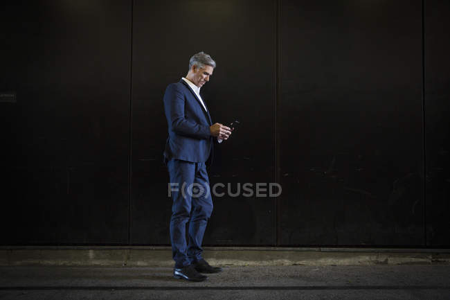 Businessman standing in shadow on city street — Stock Photo