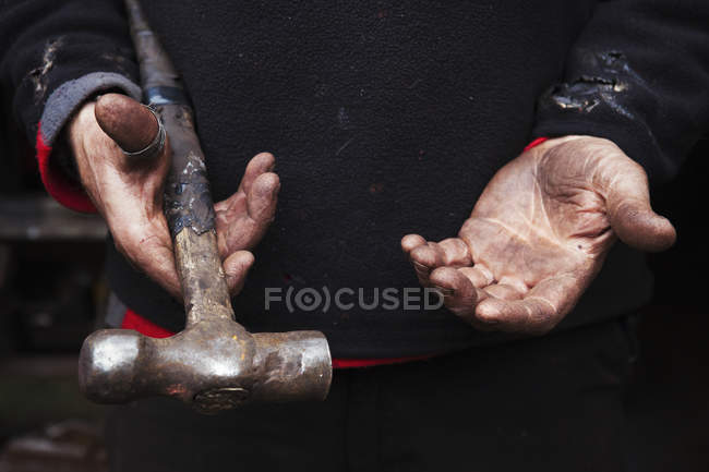 Ferreiro segurando um martelo de metal . — Fotografia de Stock
