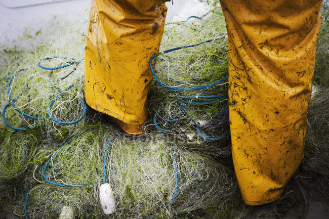 Рыбак, стоящий на грудах рыболовных сетей . — стоковое фото