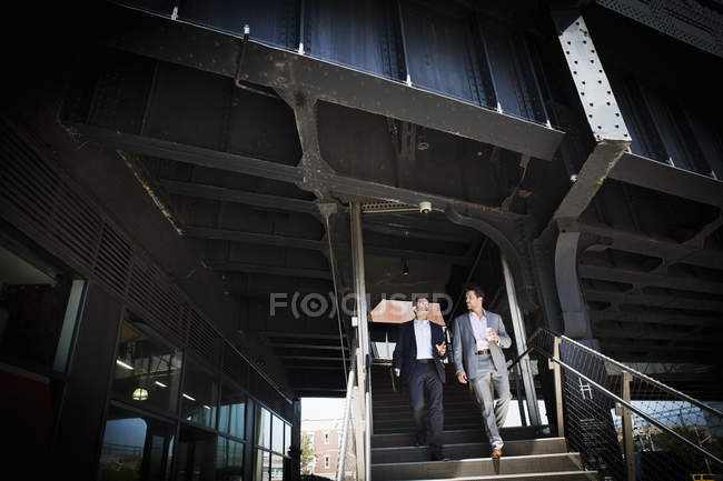 Businessmen walking down staircase — Stock Photo