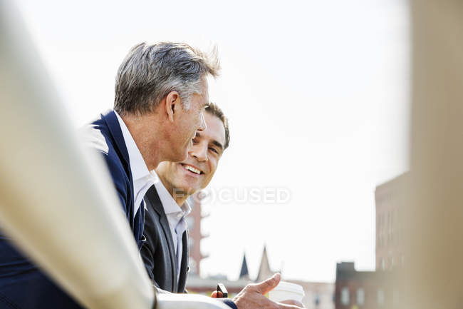 Men talking together leaning on railing — Stock Photo