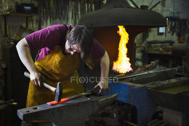 Ferreiro atinge um comprimento de metal quente — Fotografia de Stock