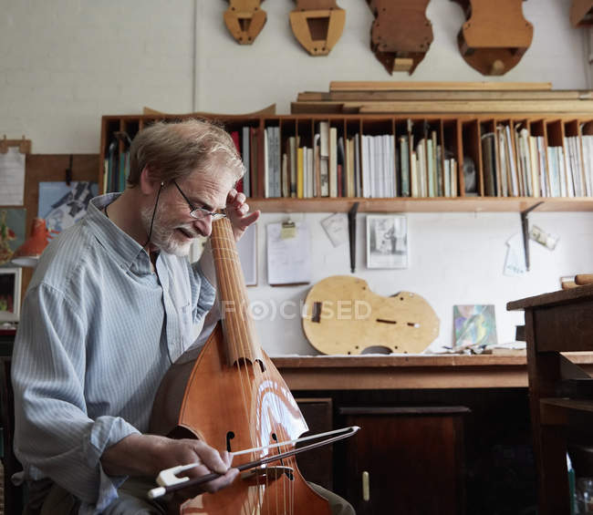 Скрипка виробник грає на інструменті з бантом — стокове фото