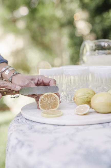 Femme tranchant des citrons pour un verre . — Photo de stock