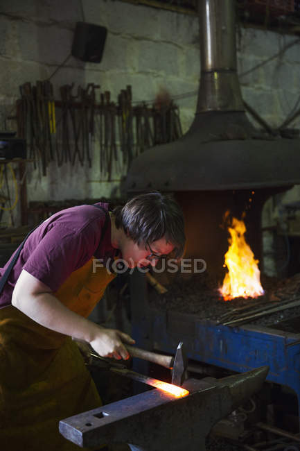 Forgeron frappe une longueur de métal chaud — Photo de stock